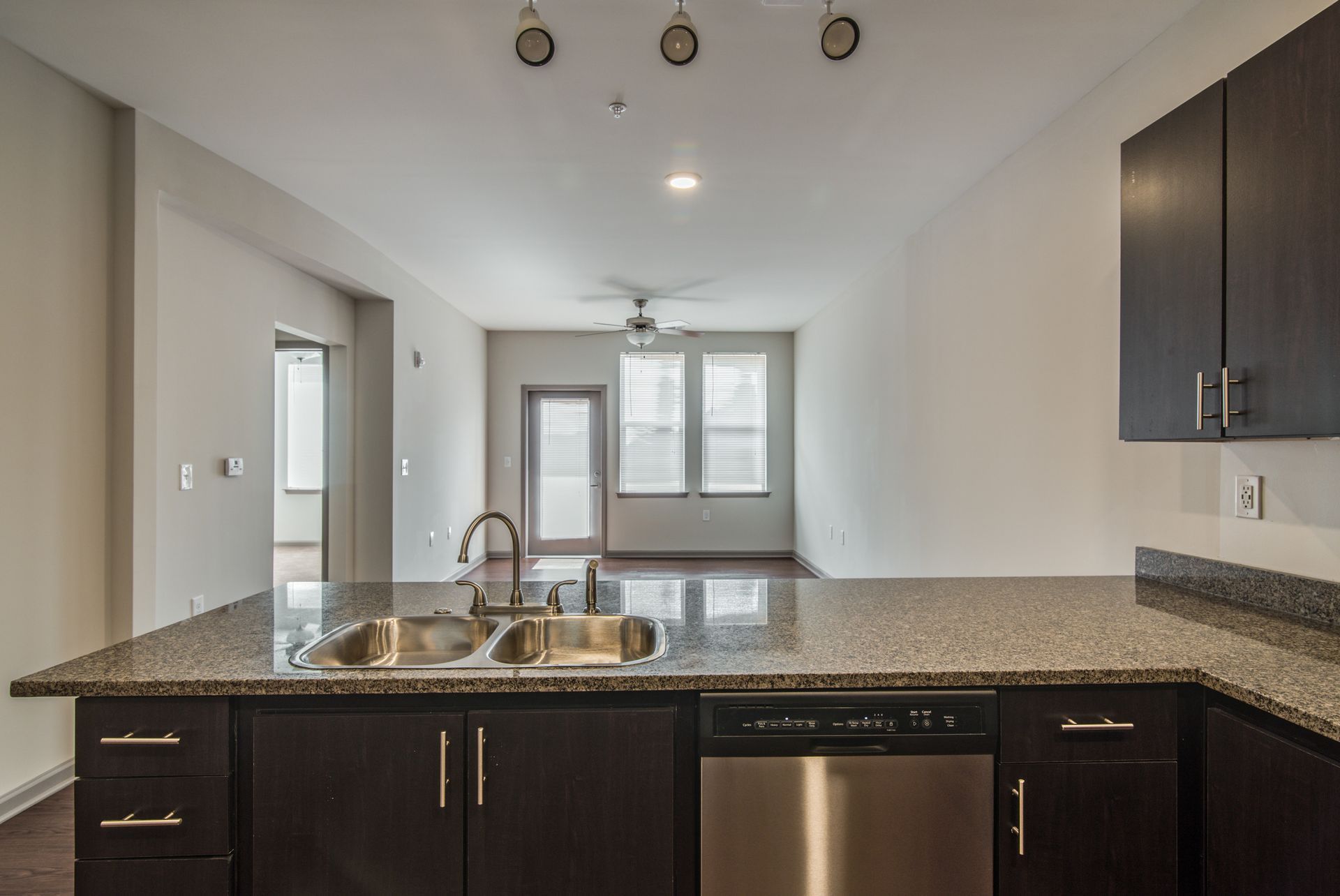 Kitchen with granite countertop, stainless steel sink and appliances, and dark cabinets at Marvel Apartments.