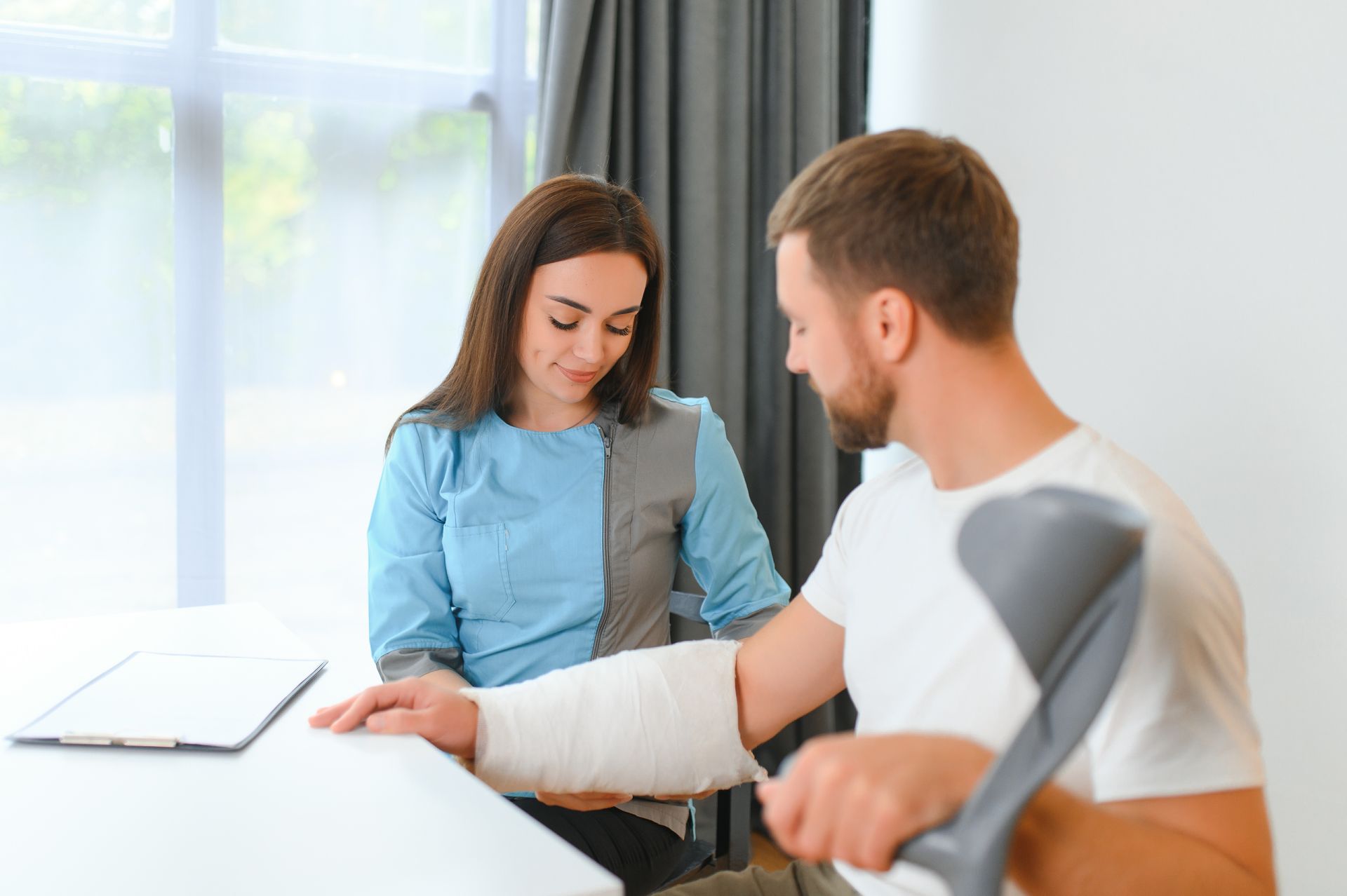Man with a cast on his arm receives help from a woman in a bright office
