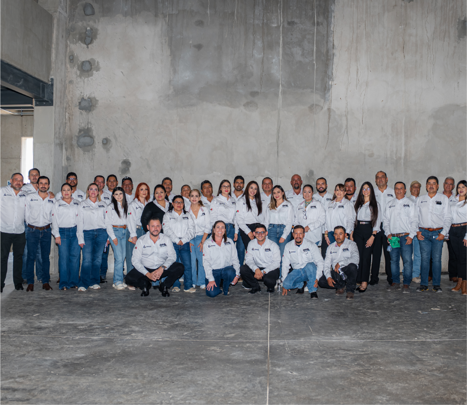 Un grupo de personas con camisas blancas y pantalones vaqueros posa frente a un muro de hormigón.