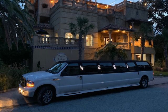 White limousine parked in front of a large, ornate building with lights on.