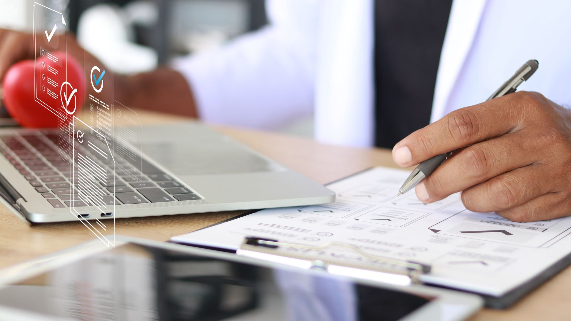 Woman in a light blue shirt working on a laptop in a bright office, focused and taking notes.