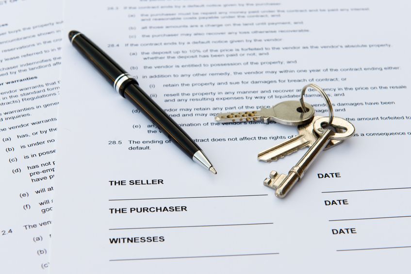 A pen and keys are on top of a contract