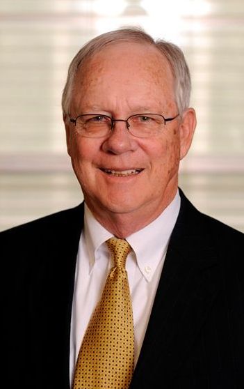 A man in a suit and tie is smiling for the camera