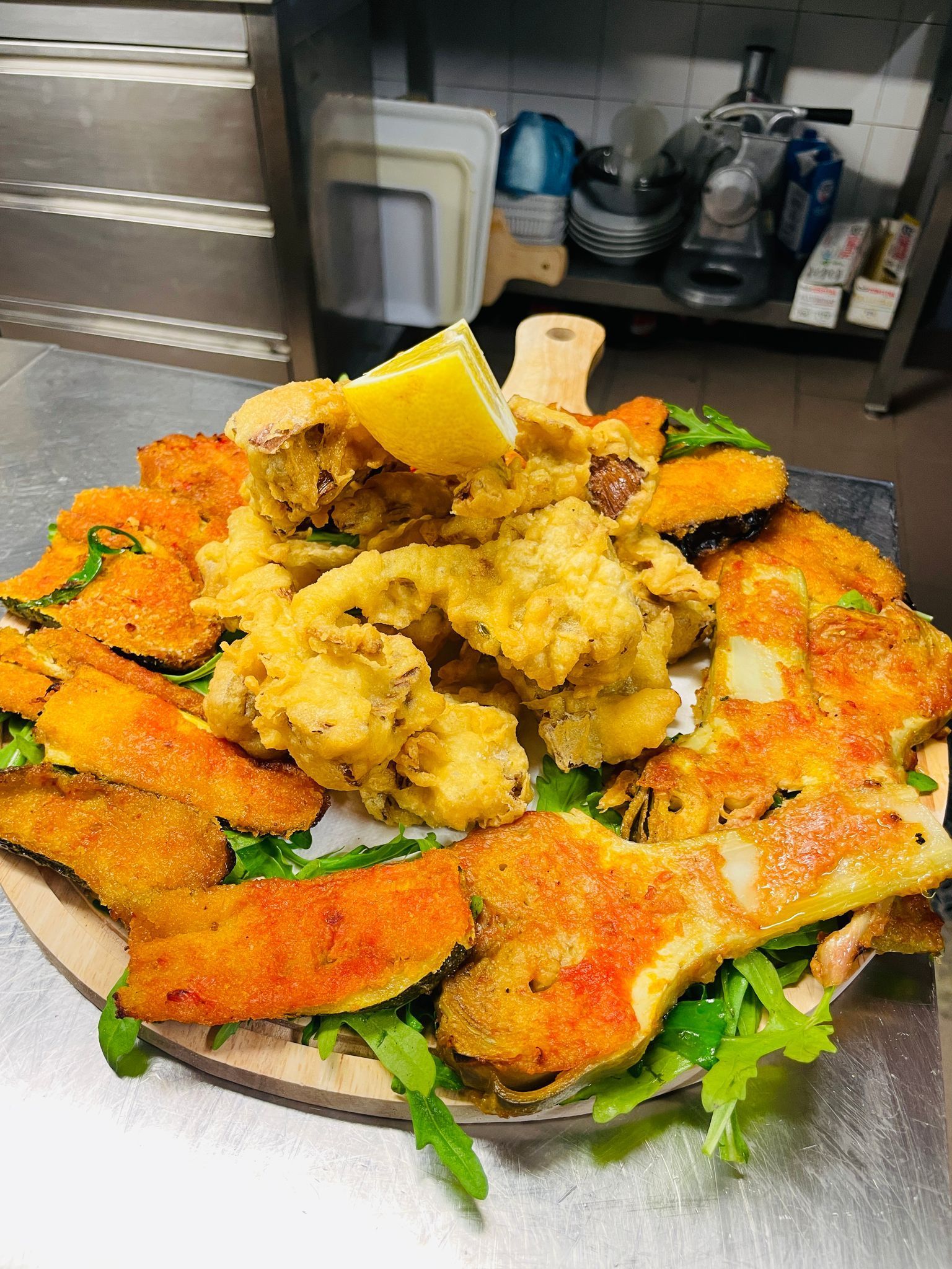 Un piatto di pesce fritto con spicchio di limone e verdure.
