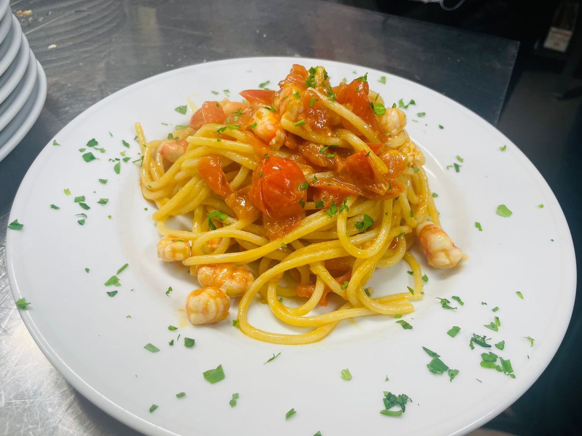 Spaghetti con gamberi e salsa di pomodoro su un piatto bianco, guarnito con prezzemolo.