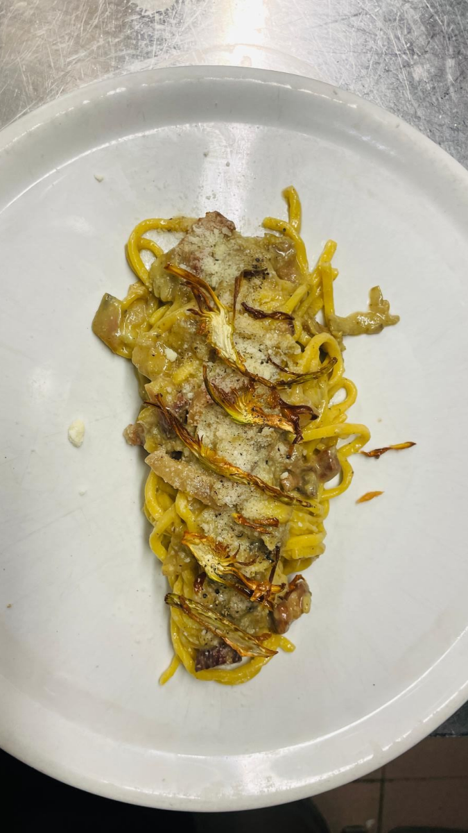 Pasta alla carbonara su un piatto bianco, guarnita con guanciale croccante e formaggio grattugiato.