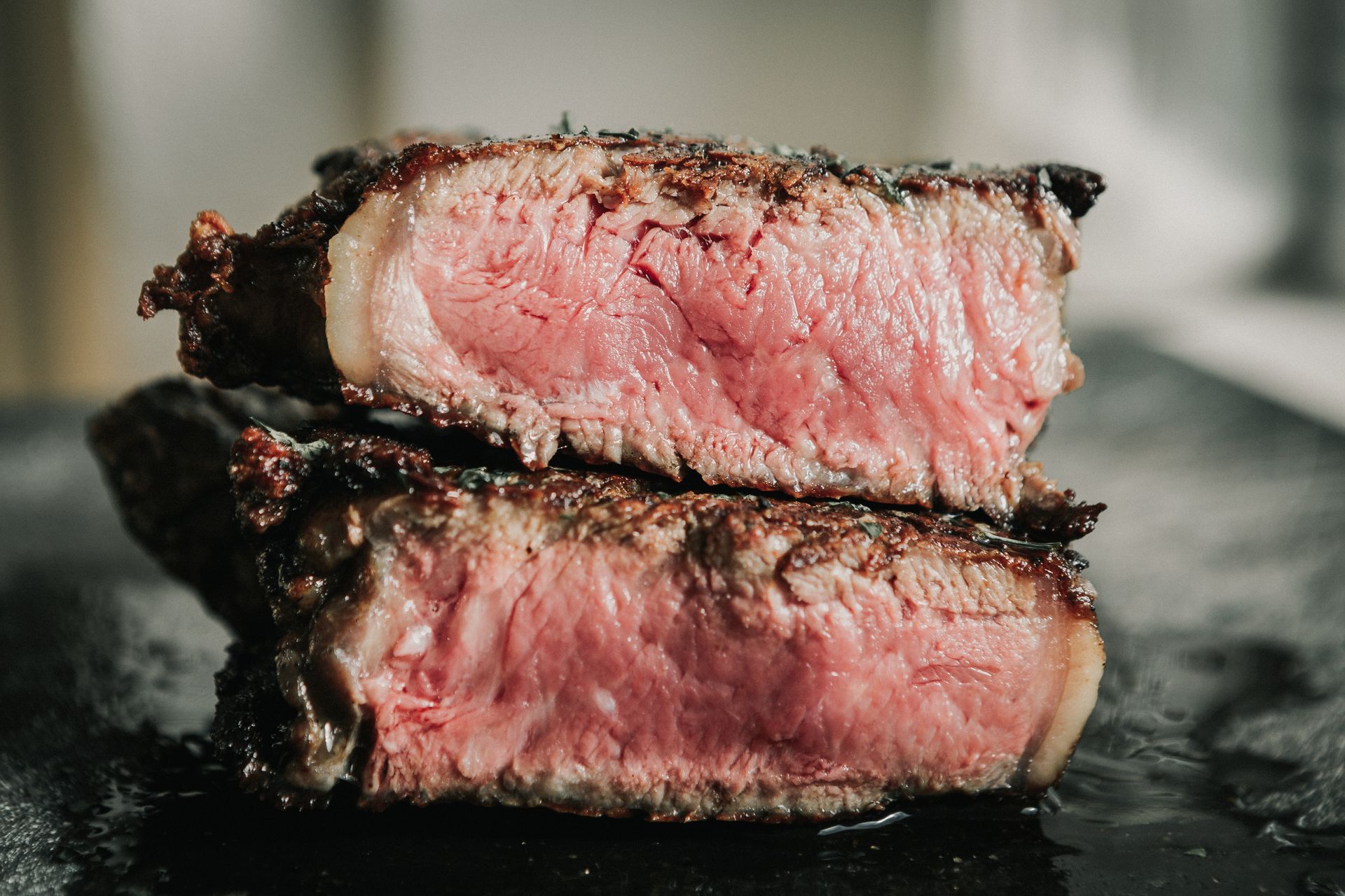 Bistecca tagliata al sangue su una superficie scura, con centro rosa e crosta scottata.