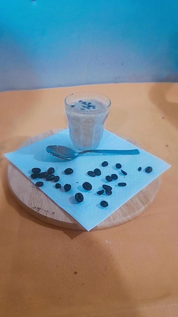Un bicchiere di dessert con gocce di cioccolato su un tagliere di legno con tovagliolo e cucchiaio.