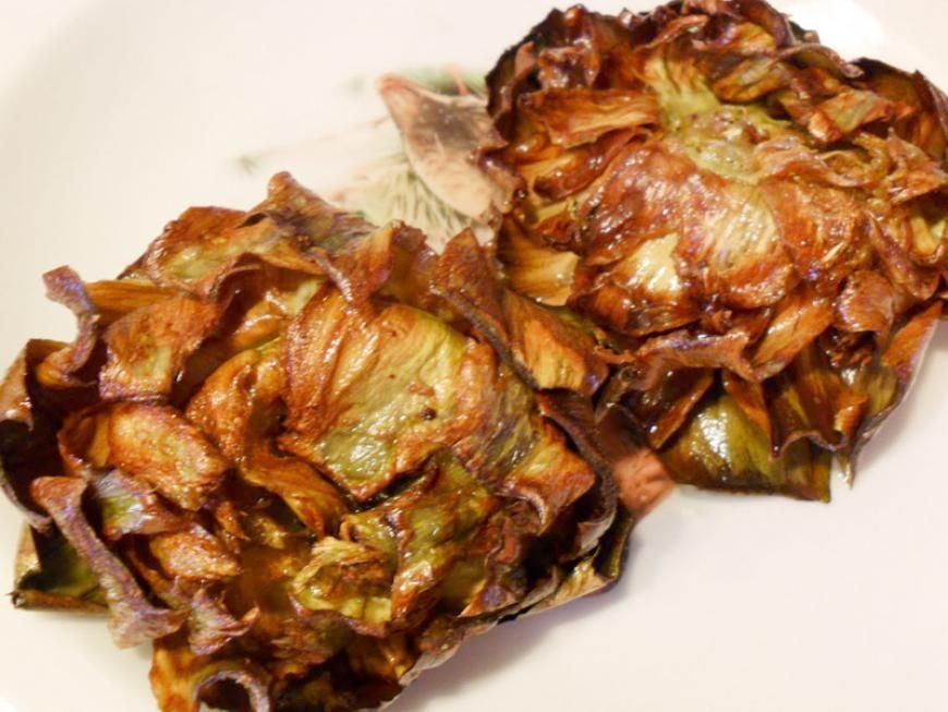 Due carciofi fritti su un piatto bianco, dorati e verdi.