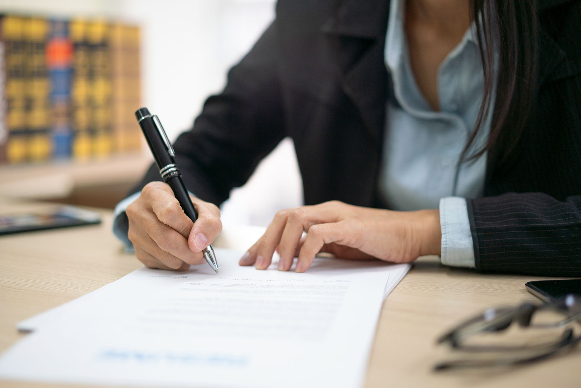 A woman is writing on a piece of paper with a pen.