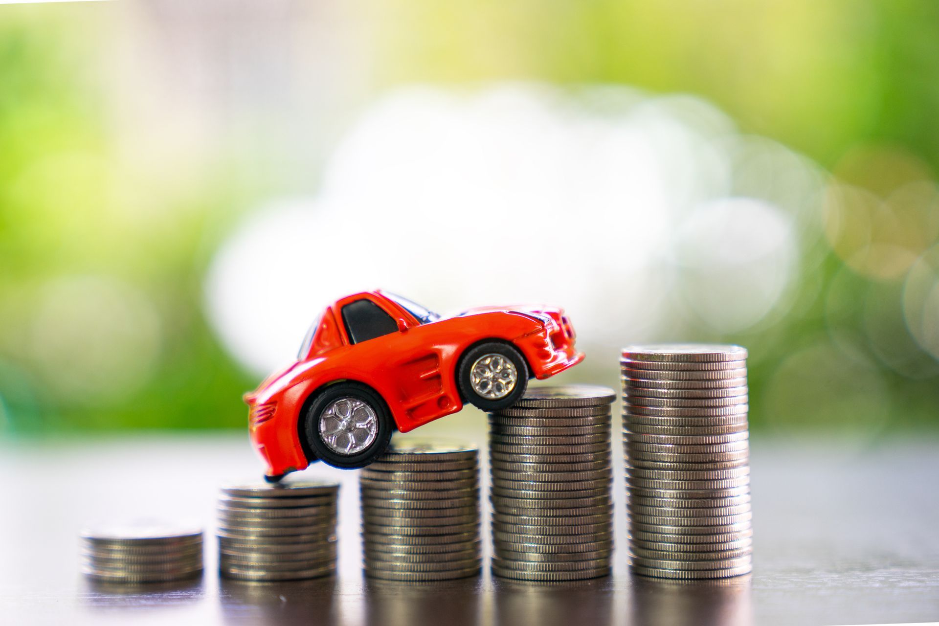 A toy car is sitting on top of a pile of coins. A toy car is sitting on top of a pile of coins.
