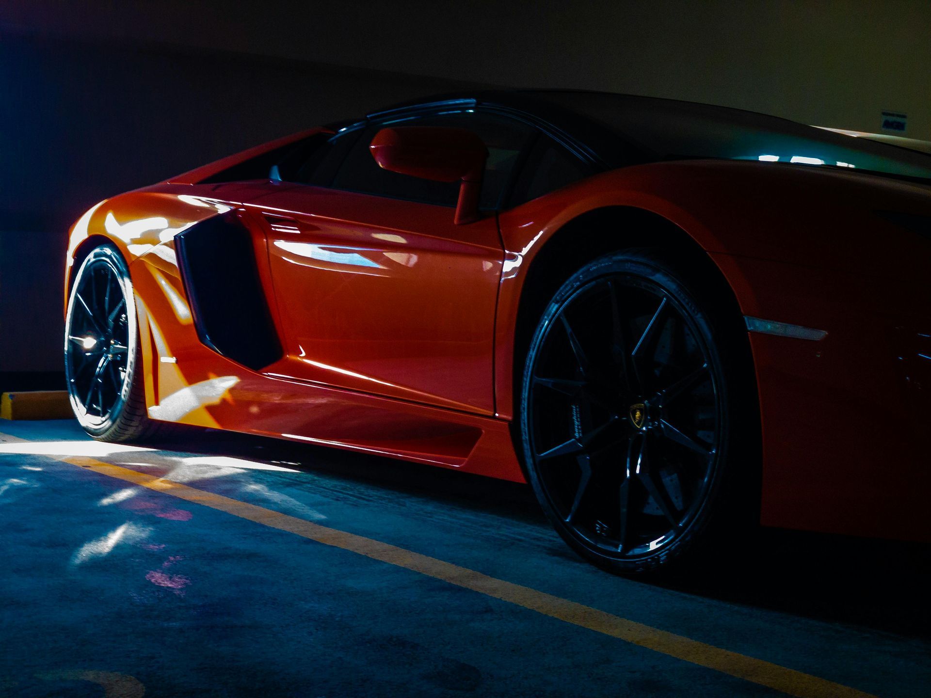 Red Lamborghini car parked in a dark garage, side view.