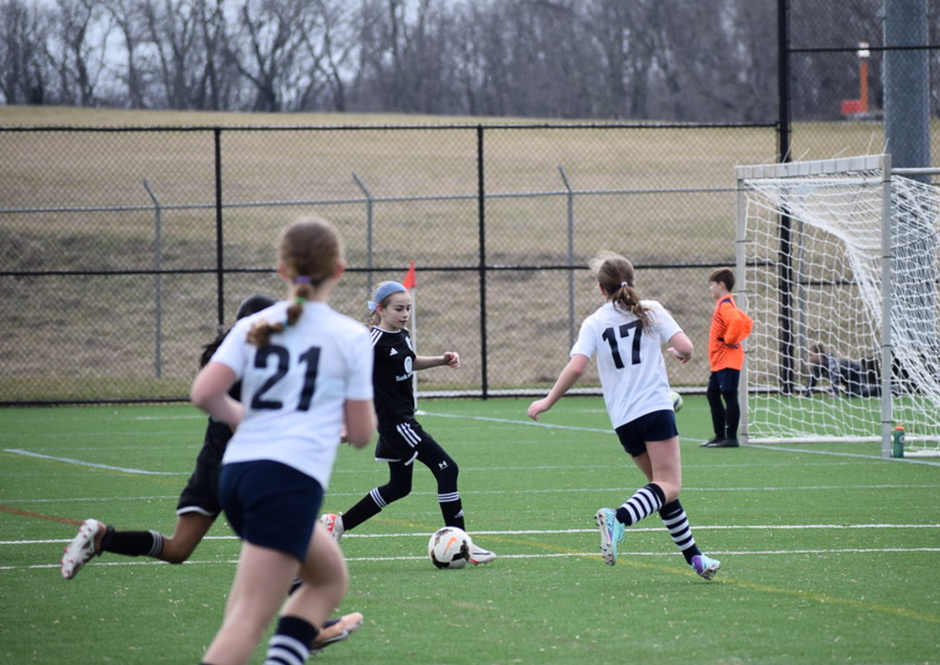 Soccer game in progress; players in white and black uniforms on green field.