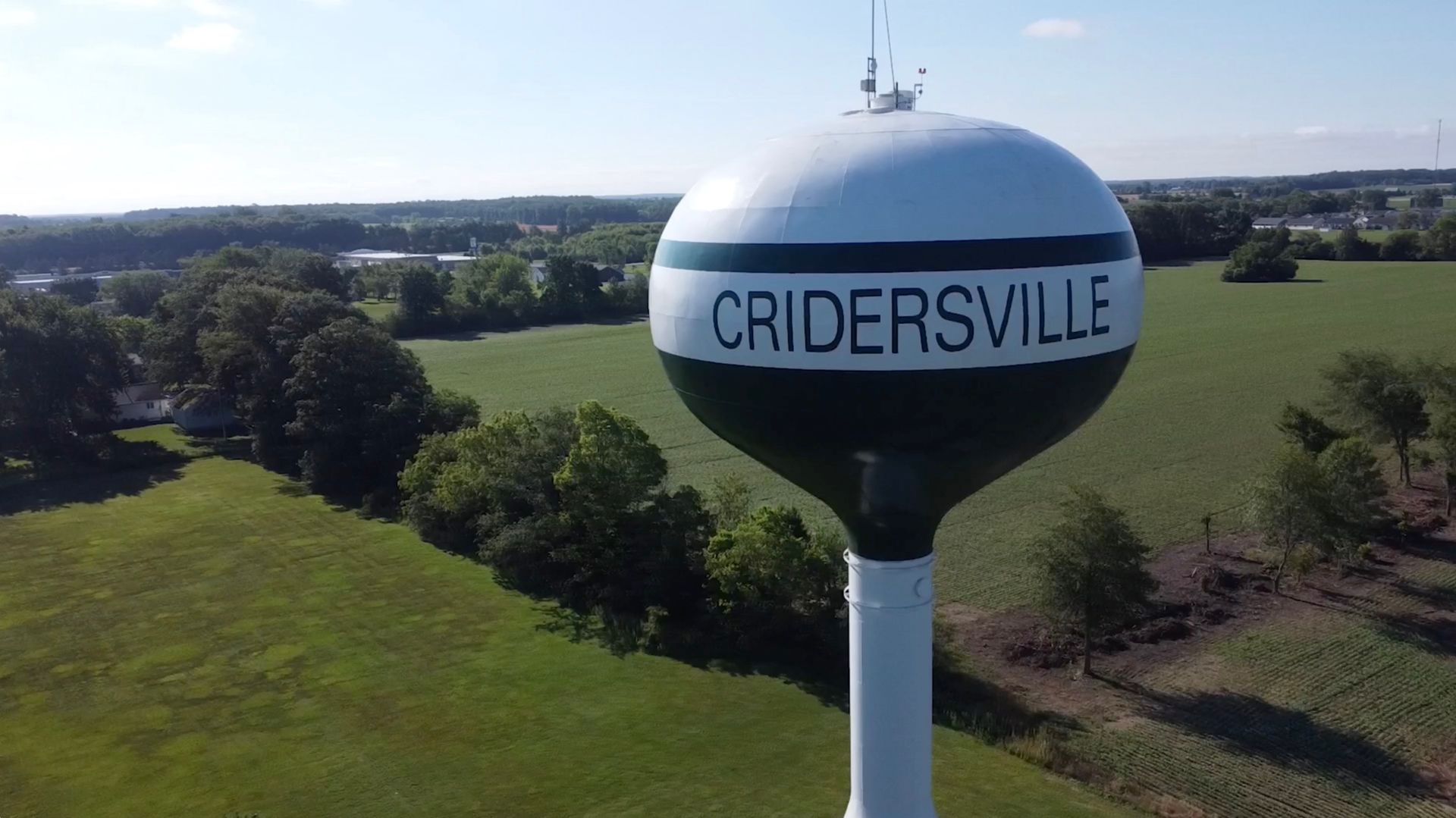 Water tower in Cridersville, Ohio, with green and white paint, in a rural landscape.