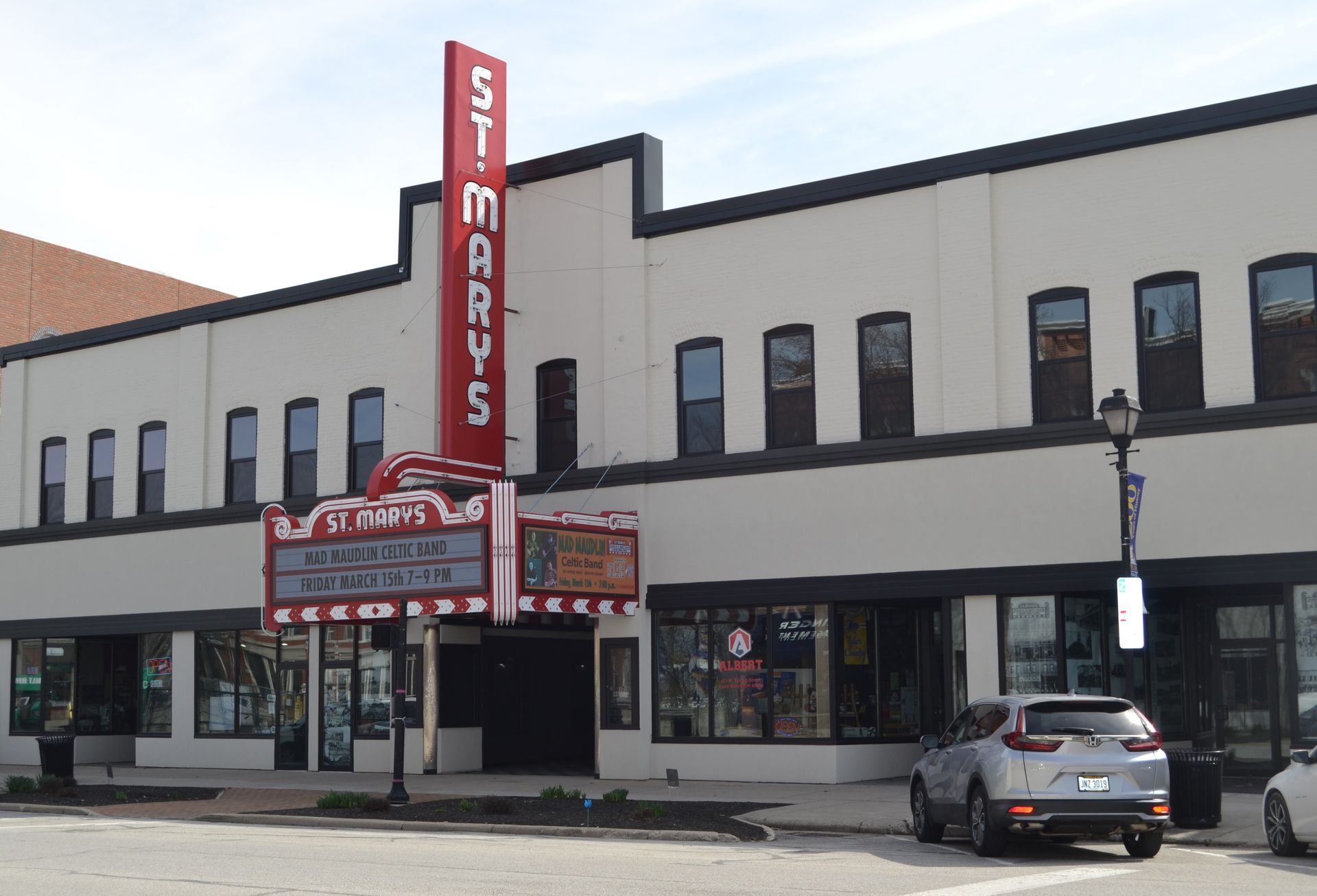 St. Mary's Theatre exterior with red sign, marquee, and parked car on a city street.