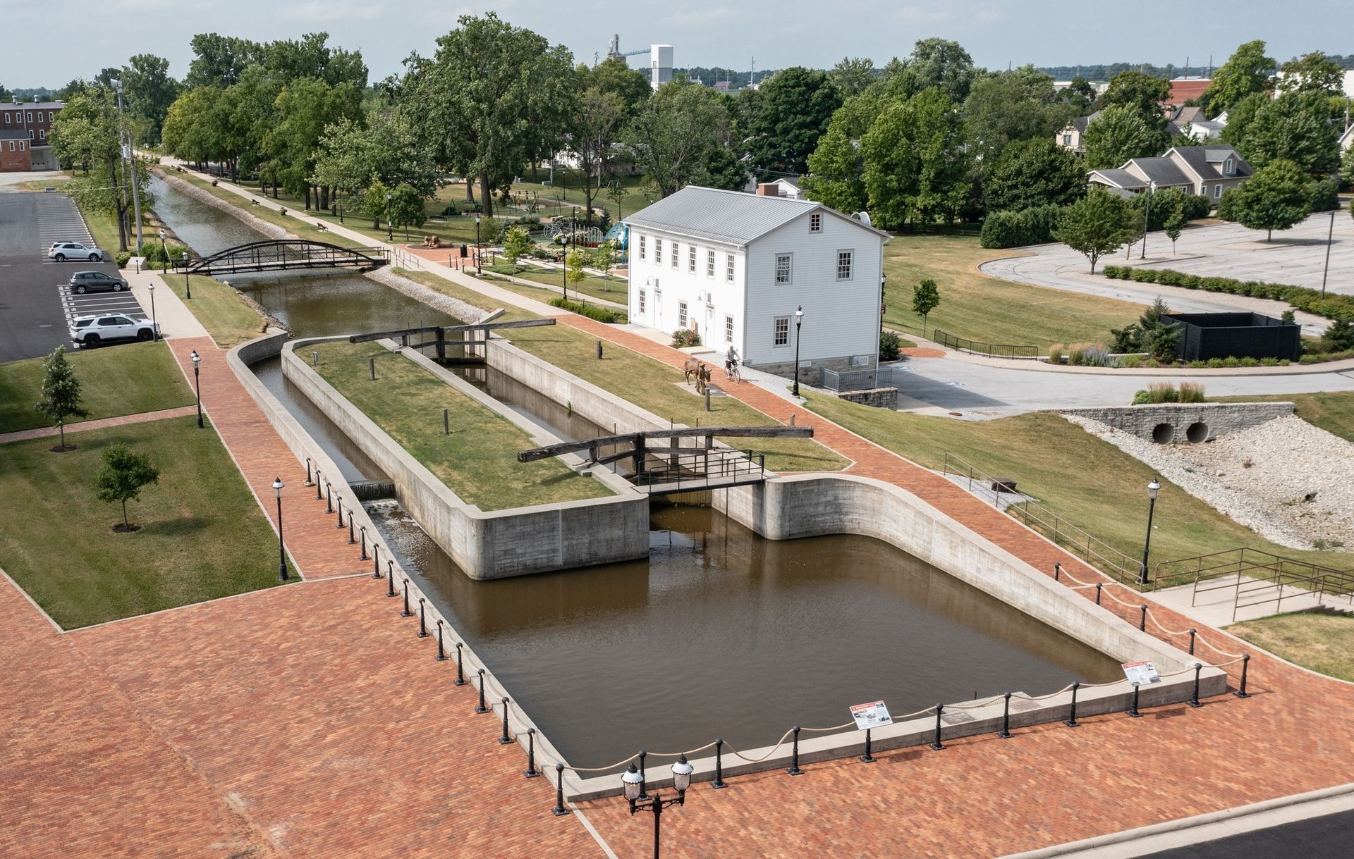 Canal lock system with brick pathways, grassy areas, and a white building.