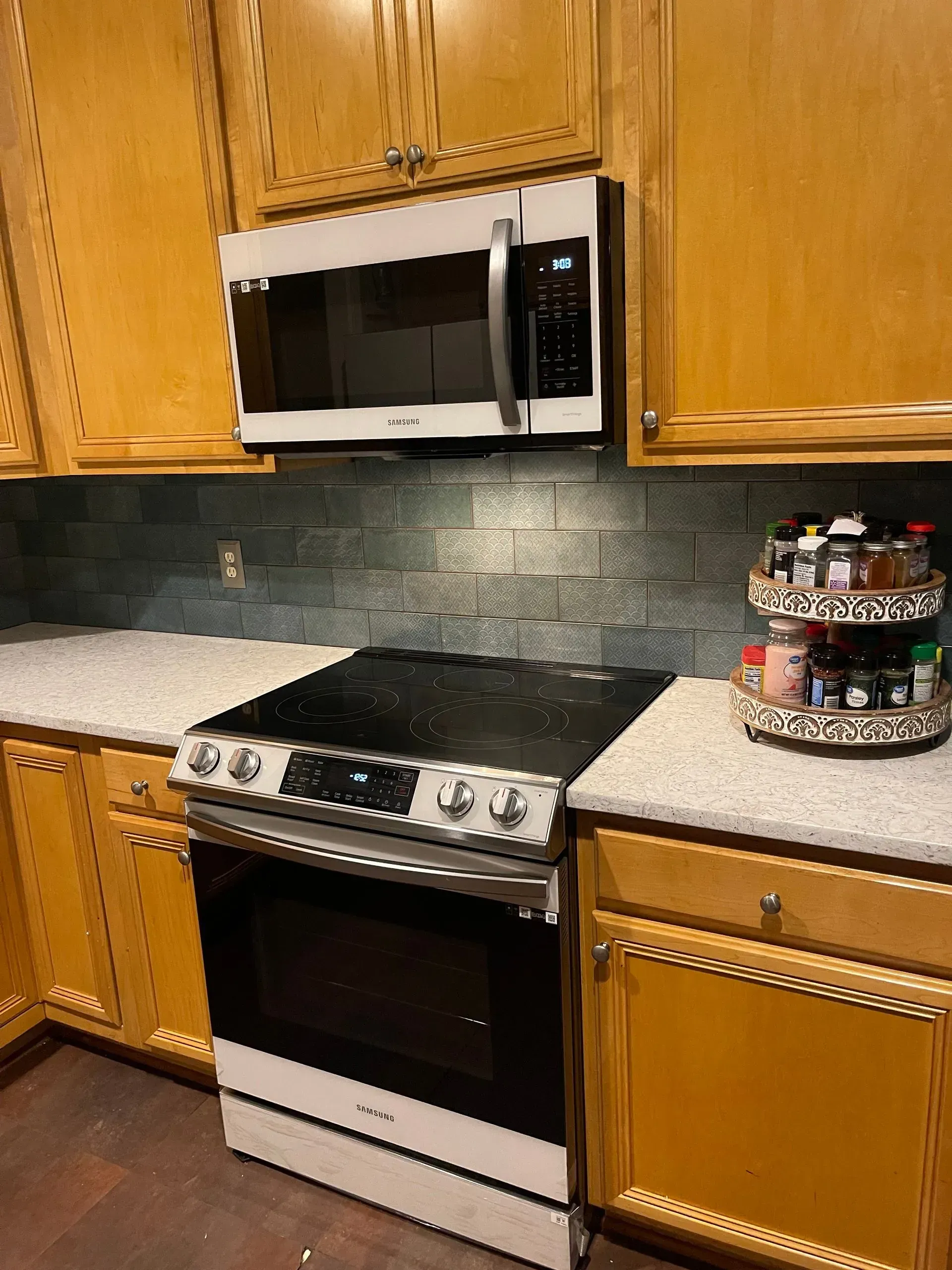 Kitchen with wooden cabinets, white countertops, stainless microwave and stove, and a cake stand on the right.