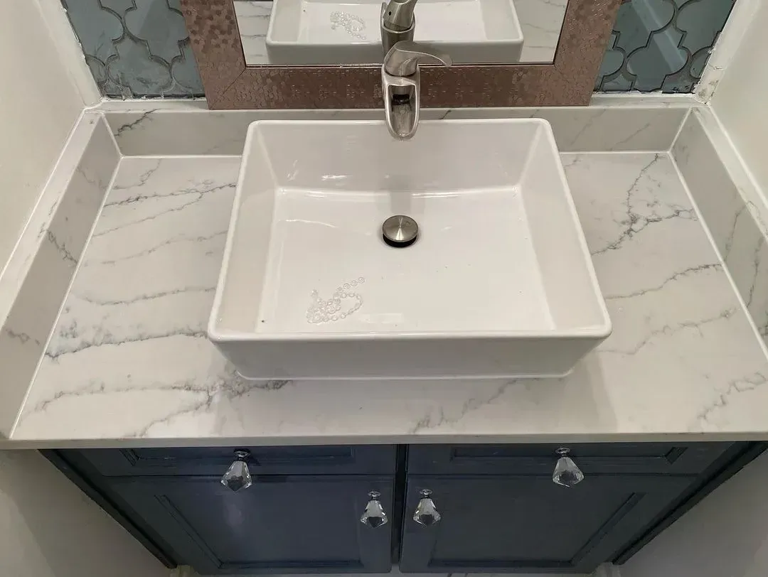 White square vessel sink on marble vanity with chrome faucet and dark blue cabinet doors