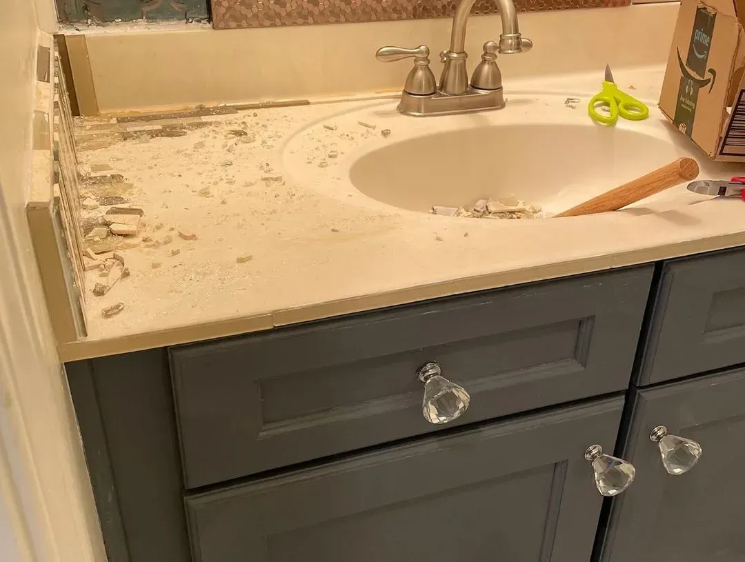 Messy bathroom sink countertop with scattered debris and a gray vanity below