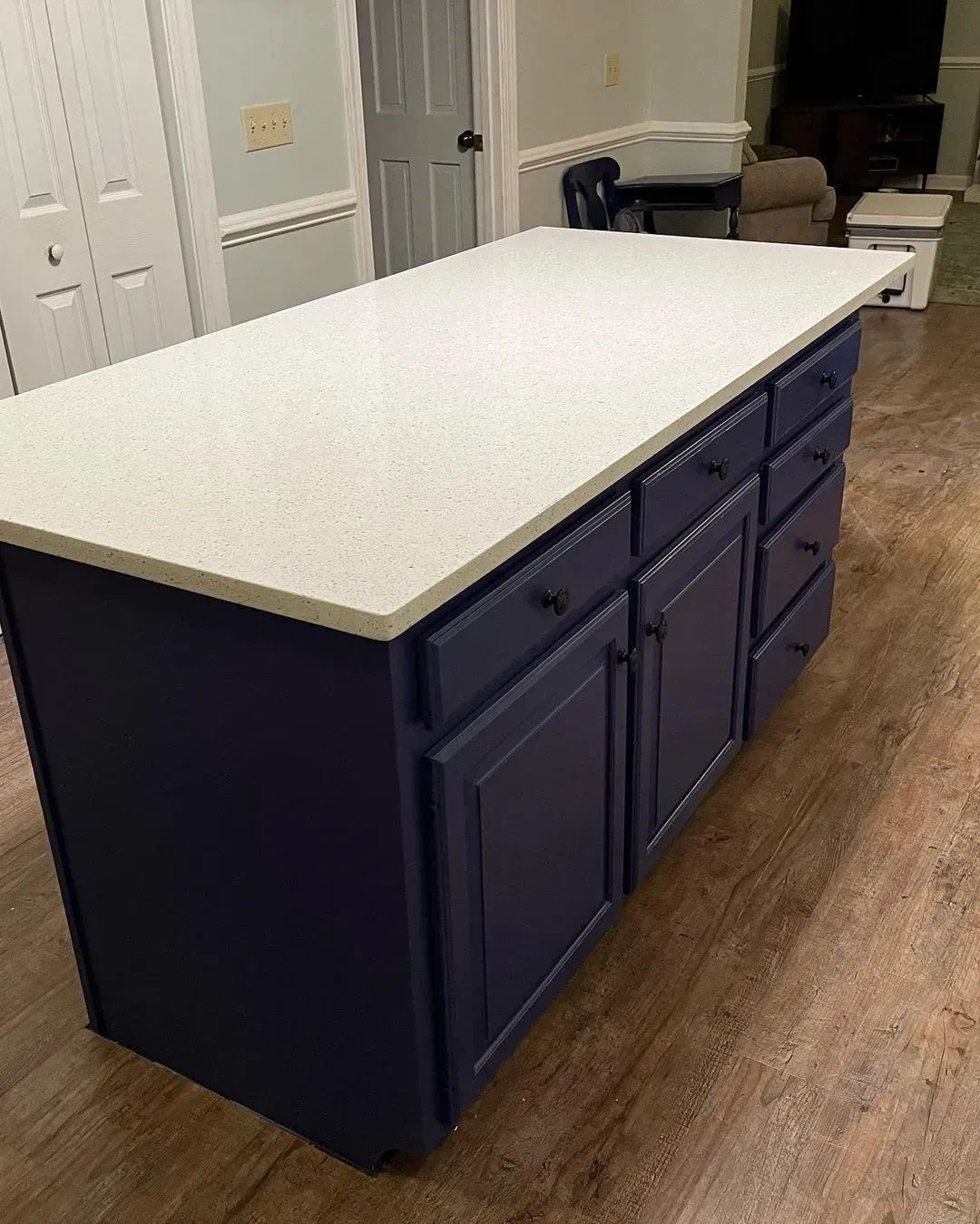 Dark blue kitchen island with white countertop in a hallway or kitchen interior.