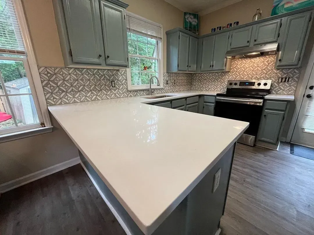 Modern kitchen with white island, gray cabinets, and stainless steel appliances