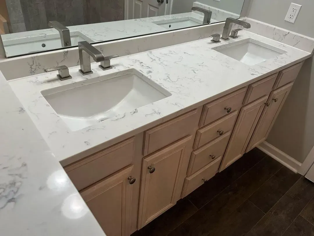 Double vanity bathroom with white countertop, two sinks, and beige cabinets near a large mirror