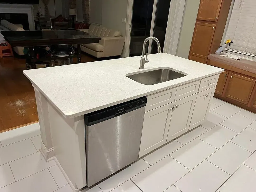 Modern kitchen island with white countertop, stainless sink, and built-in dishwasher