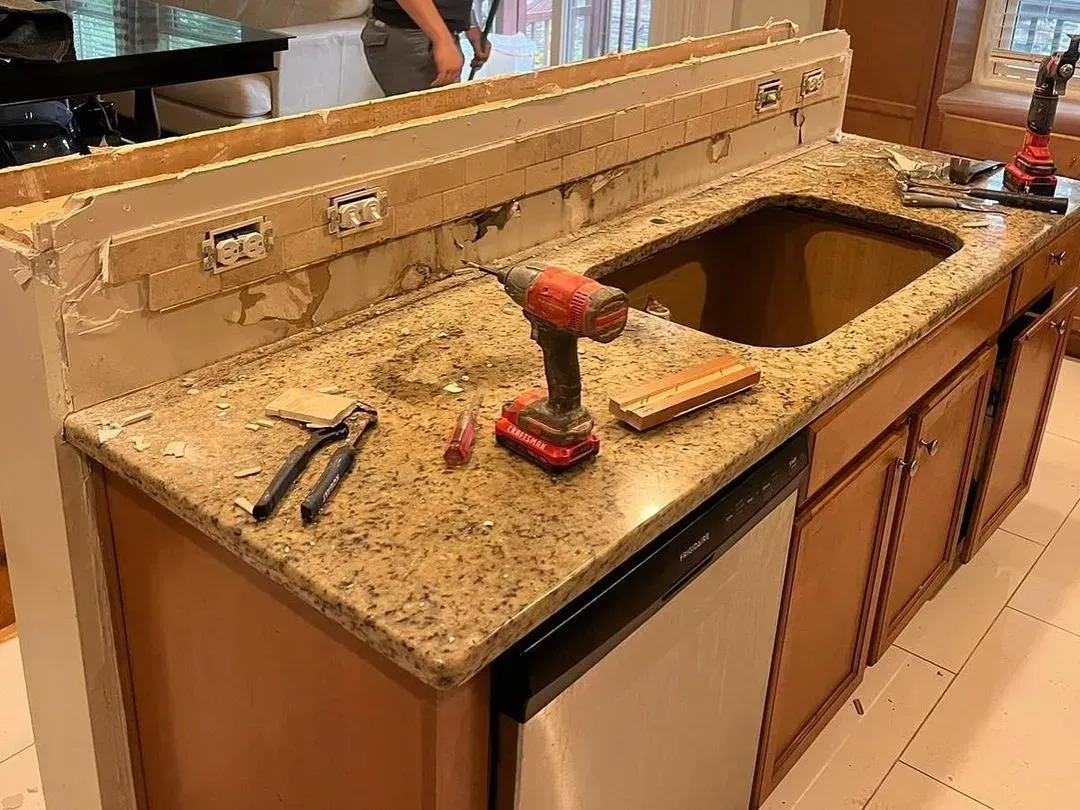 Kitchen sink countertop with a drill and tools, showing a sink installation in progress