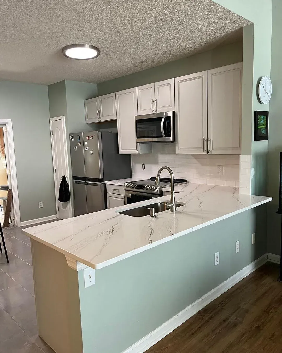Modern kitchen with white cabinets, stainless appliances, and a large white island countertop.