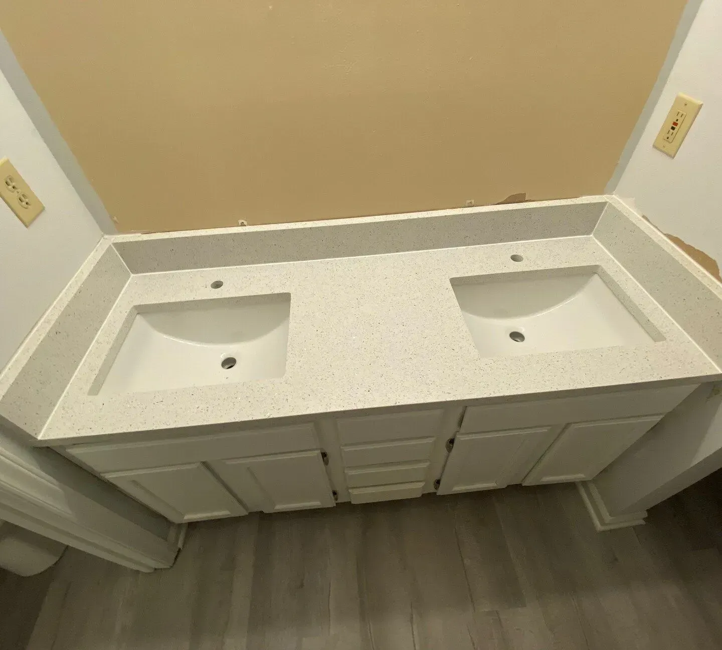 White double-sink bathroom vanity with granite countertop and gray flooring, viewed from above.