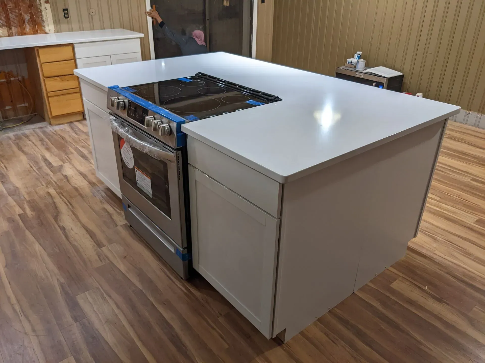 Kitchen island with white countertop and a stainless steel stove in a room with wood flooring