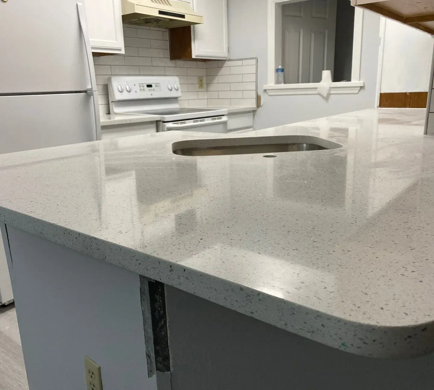 White speckled kitchen island countertop with built-in sink in a bright kitchen