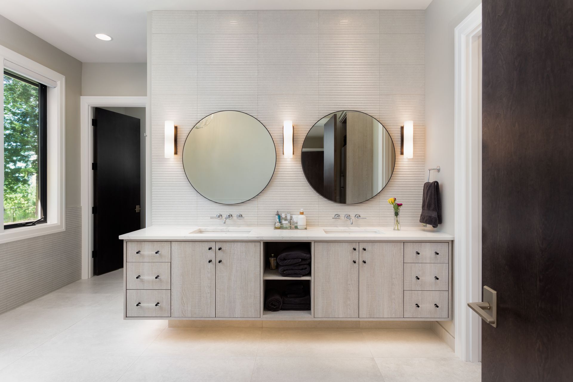 Modern bathroom vanity with two round mirrors, white cabinetry, and dark wood doors. Modern bathroom vanity with two round mirrors, white cabinetry, and dark wood doors.