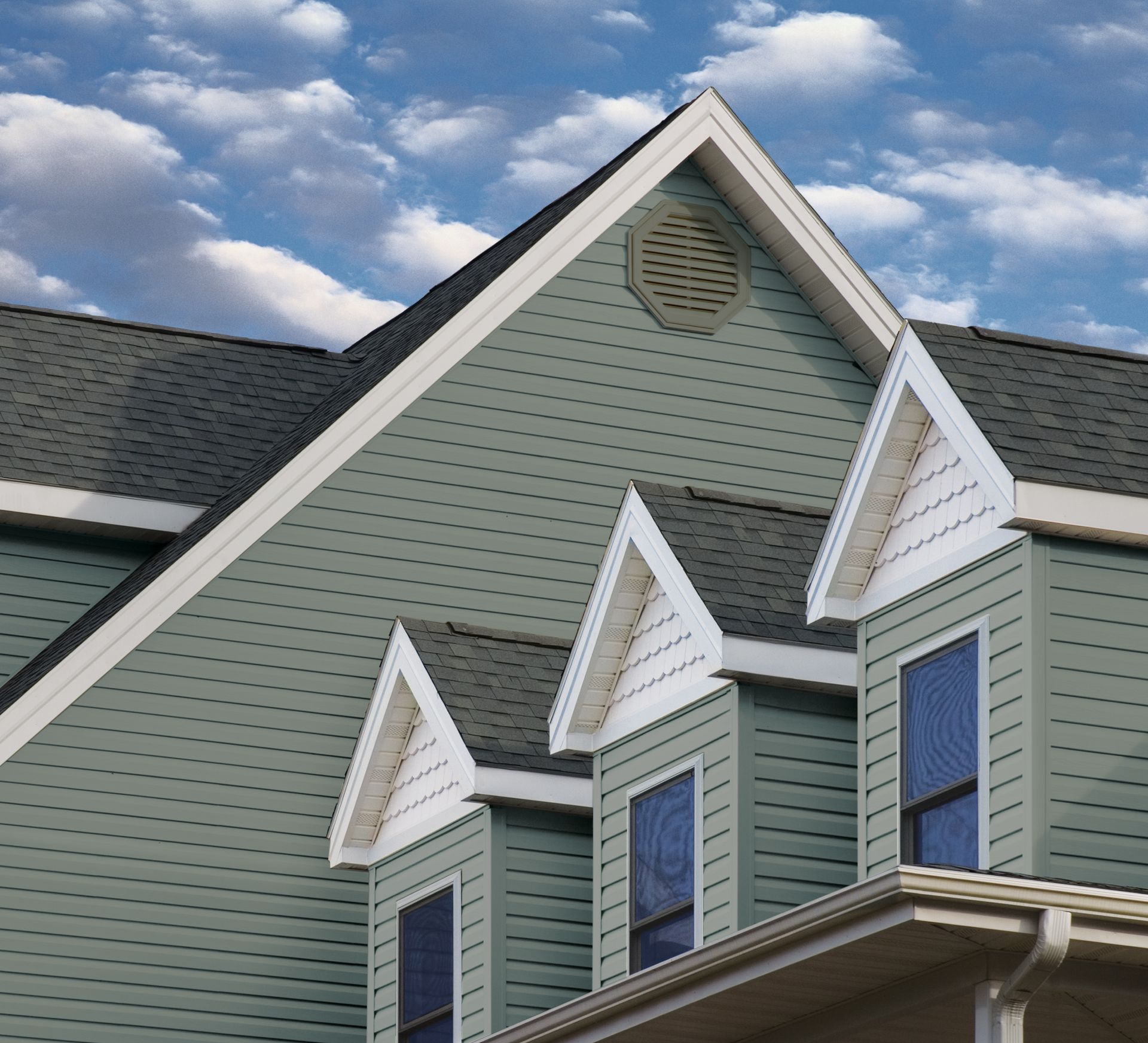 Green house gables with white trim against a blue sky with clouds
