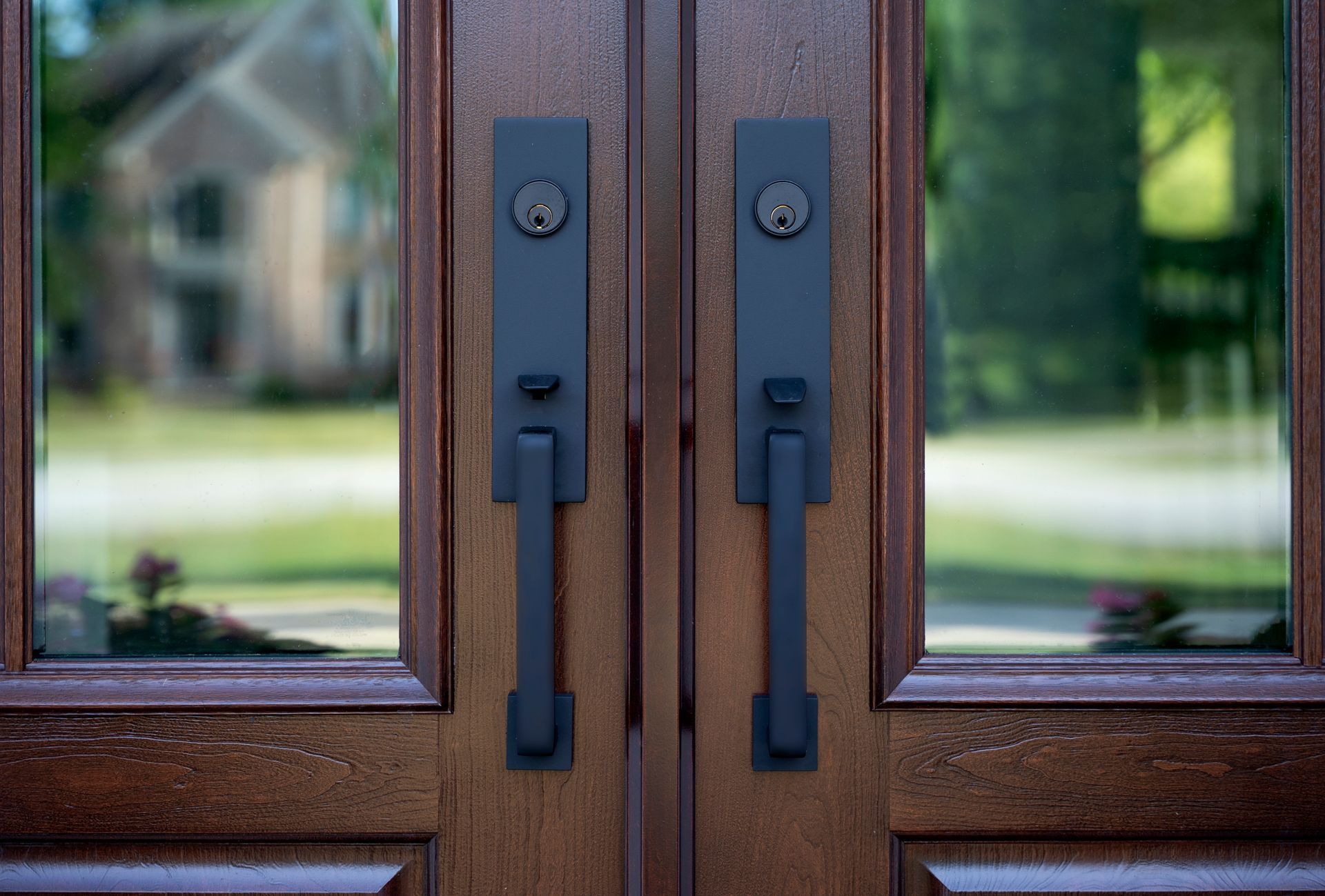 Close-up of wooden double doors with black metal handles and glass panels Close-up of wooden double doors with black metal handles and glass panels