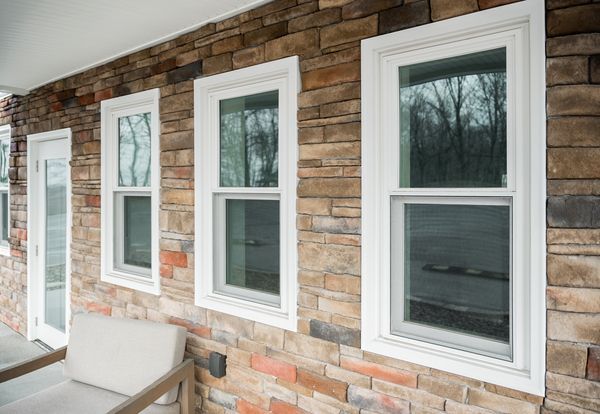 Brick house exterior with four white-trimmed windows and a bench on the porch Brick house exterior with four white-trimmed windows and a bench on the porch