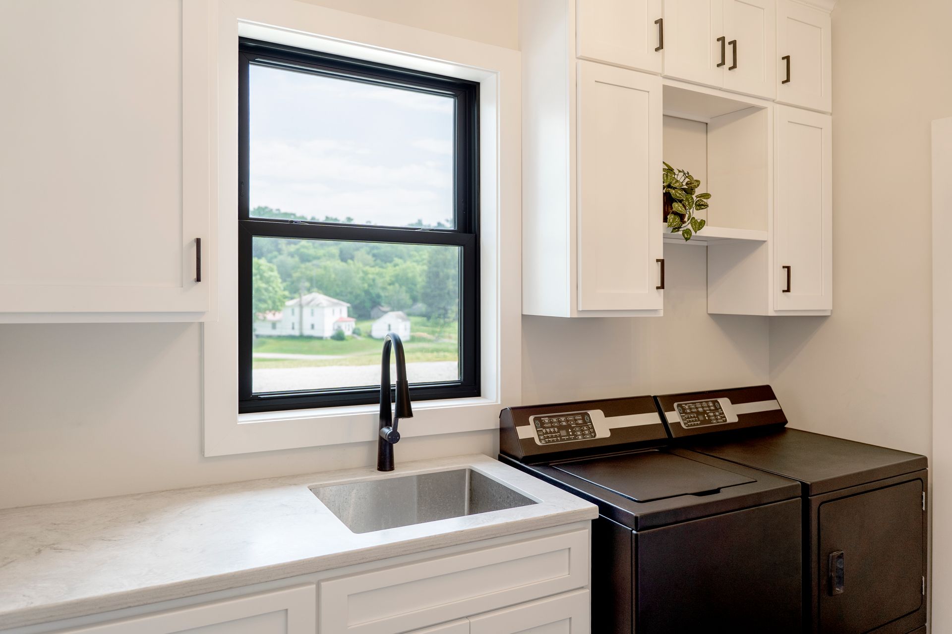Modern kitchen with white cabinets, black sink faucet, and black appliances by a window. Modern kitchen with white cabinets, black sink faucet, and black appliances by a window.