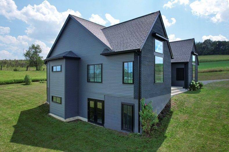 Professional replacement window installation on a modern home exterior with coal black casement and picture windows.