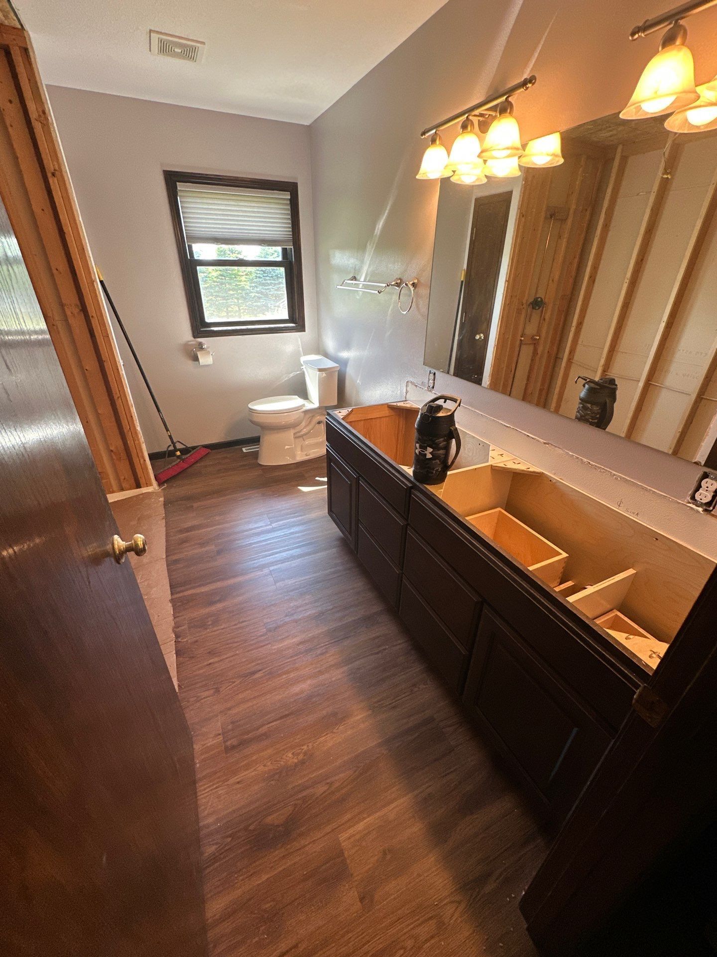 Modern bathroom with gray tiles, glass shower, vanity sink, and toilet under warm lighting Modern bathroom with gray tiles, glass shower, vanity sink, and toilet under warm lighting