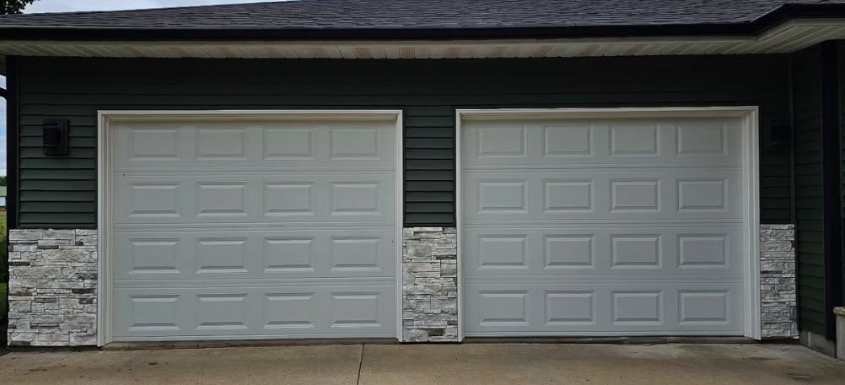 Two gray garage doors on a house exterior with stone and dark siding trim