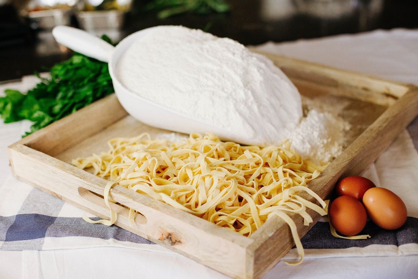 Forma di formaggio con formaggio grattugiato e tre uova in una cassetta di legno su un tavolo da cucina.