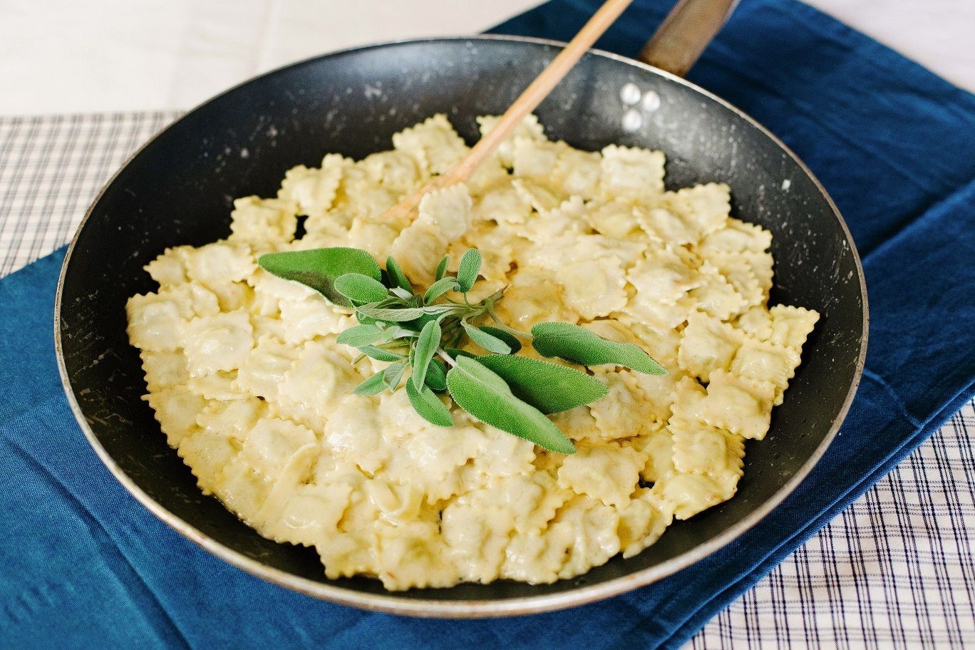 Riso fritto in una padella nera, guarnito con erbe aromatiche, su un tovagliolo blu.