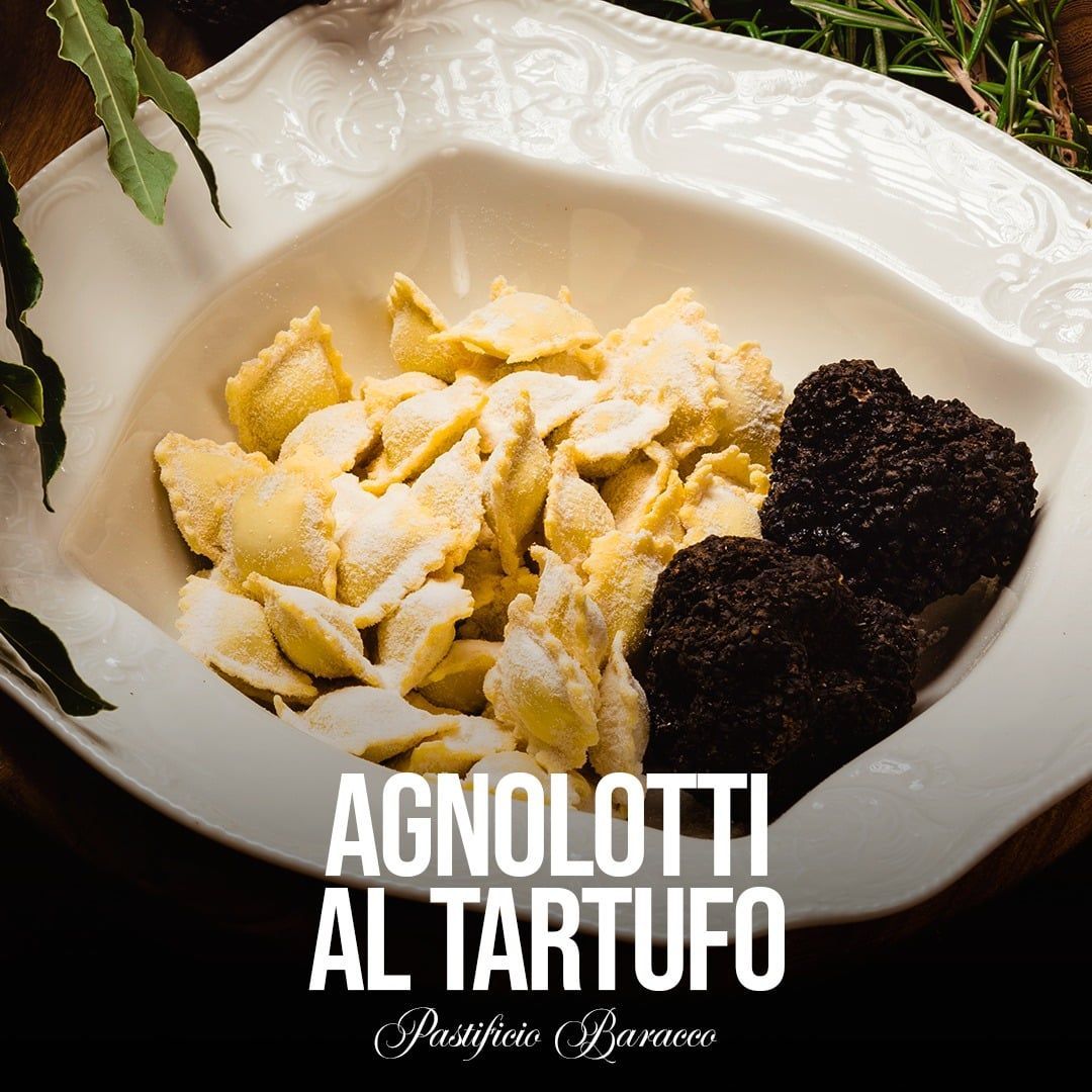 Agnolotti al tartufo nero serviti su un piatto bianco, dal titolo