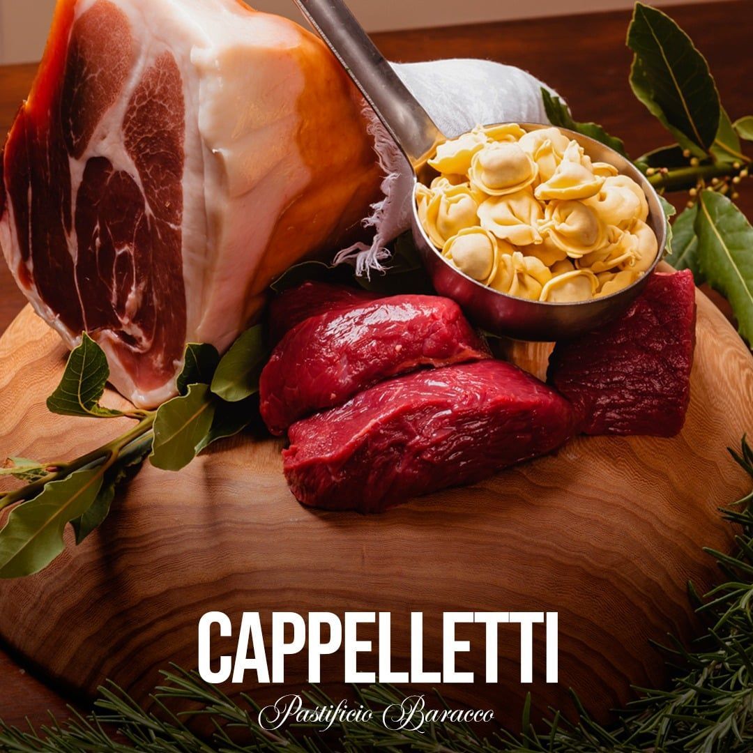 Cappelletti con prosciutto, carne rossa e sugo su tagliere di legno