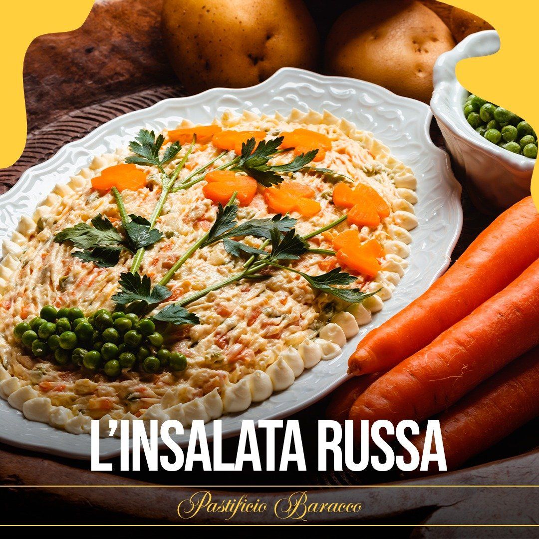 Insalata russa con piselli, carote ed erbe aromatiche su un piatto bianco, con patate e carote a lato.