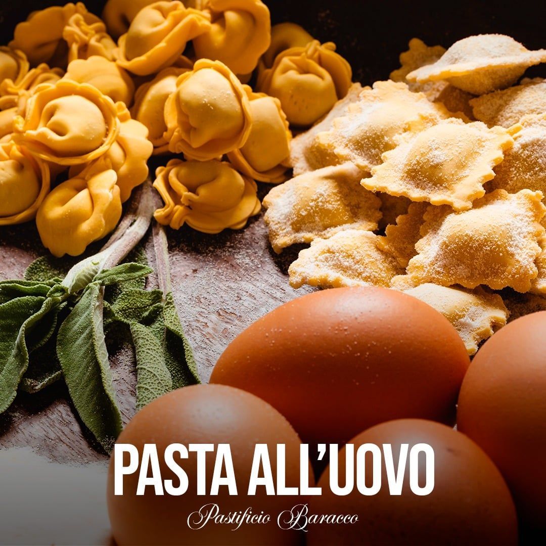 Formati di pasta fresca, uova e farina su una superficie scura con la scritta “PASTA ALL'UOVO”