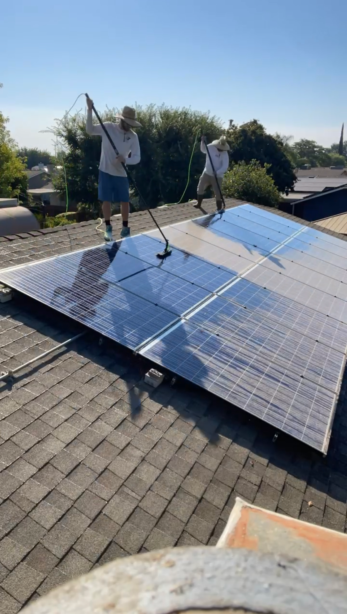A person is cleaning a solar panel with a broom.