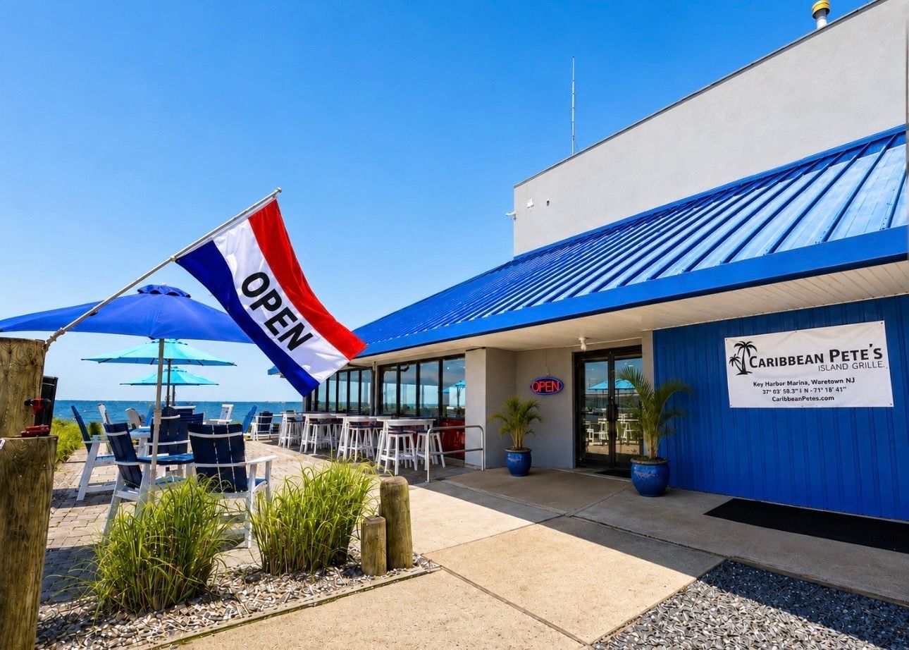Storefront with blue roof and an open flag outside a bright, sunny patio area.