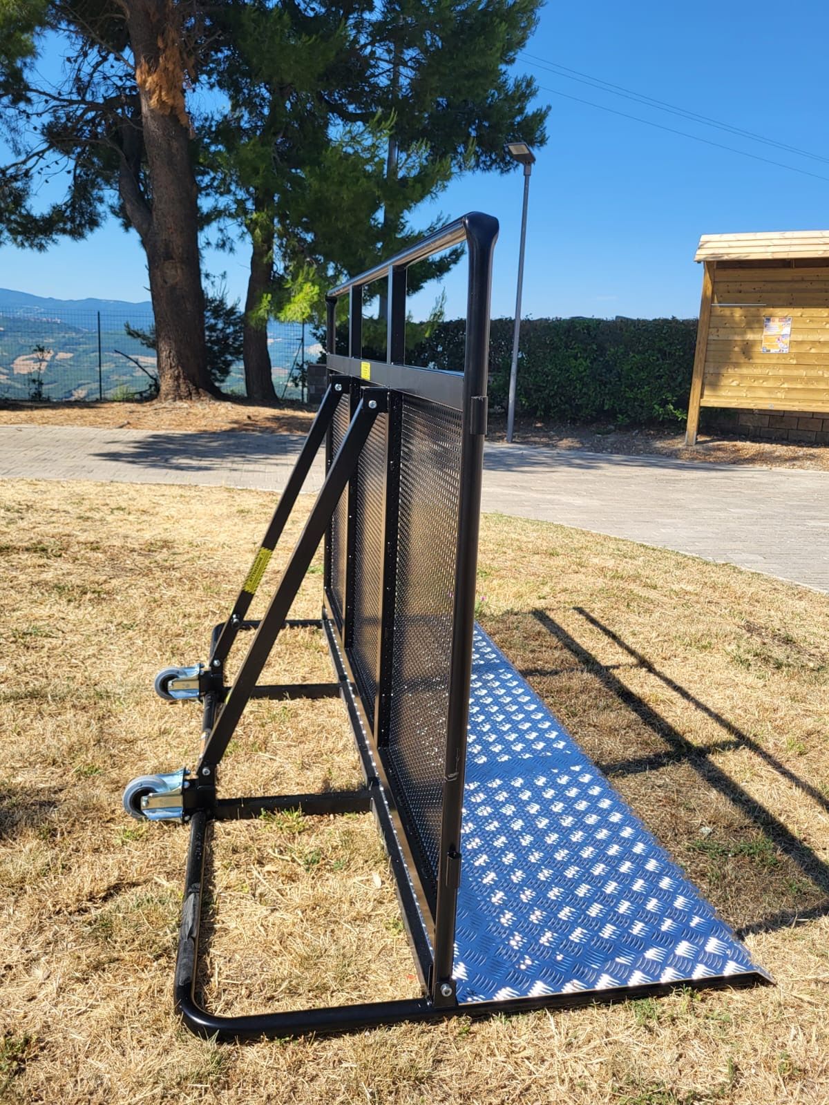 Una recinzione metallica è posta in cima a un campo di erba secca.