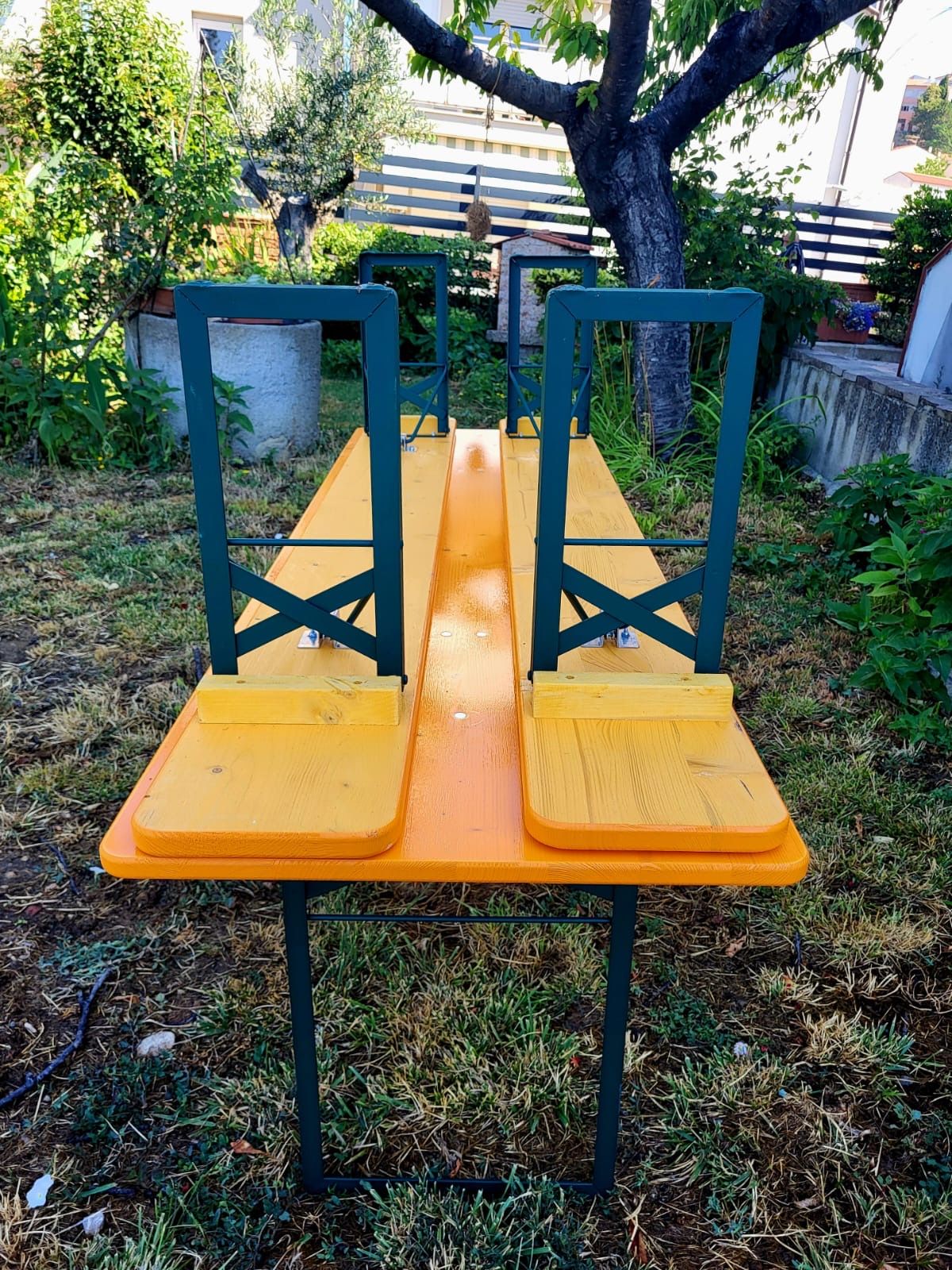 Un tavolo e delle sedie di legno sono posizionati in cima a un lussureggiante campo verde.